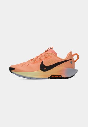 Nike running shoe in soft peach with black swoosh, lightweight mesh upper, textured accents, and a durable sole featuring orange detailing.