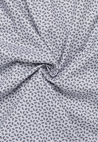 Baumwollstoff mit hellgrauem Hintergrund, der ein sich wiederholendes Muster aus kleinen, dunkelblauen, blattähnlichen Formen aufweist. Weiche Textur, gefaltetes Design.