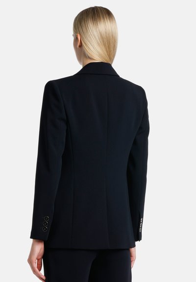 Blazer noir ajusté avec un design structuré, des revers pointus et des poignets à trois boutons, fabriqué à partir d'un tissu lisse avec une silhouette classique.