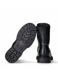 Stivaletti neri in pelle con suola in gomma texturizzata, caratterizzati da un motivo di battistrada pronunciato e una cerniera laterale per indossarli facilmente.
