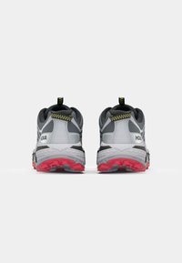 Chaussures de course grises et noires avec une semelle rouge, présentant une tige à motifs, une forme arrondie et une sangle au talon.