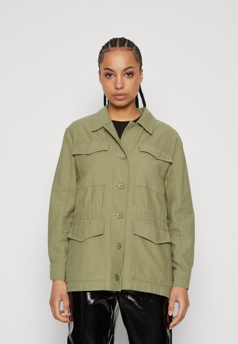 Olive green jacket with button closure, two front pockets, and a collar. Made of textured fabric, features long sleeves and relaxed fit.