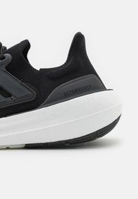 Sneakers en maille noires avec une tige texturée, design élégant, dotées d'une semelle intermédiaire blanche rembourrée et d'une semelle extérieure en caoutchouc noire. Détail embossé "ULTRAGBOOST".