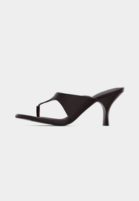 Μαύρο δερμάτινο σανδάλι με τακούνι, μυτερή μύτη, λουράκι μεταξύ δαχτύλων και μεσαίο στιλέτο τακούνι, εμφανιζόμενο από το πλάι σε λευκό φόντο.