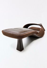 Sandale à talon bas en daim marron avec bout carré et bride à boucle, vue en angle mettant en avant les détails du talon et de la semelle.