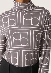 Grauer Rollkragenpullover mit weißem geometrischen Muster, das abgerundete Formen innerhalb quadratischer Rahmen zeigt, aus weichem, dehnbarem Material gefertigt.