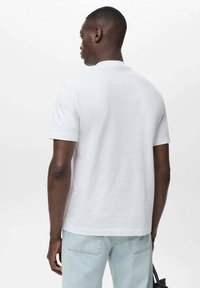 White short-sleeve t-shirt made of cotton, featuring a crew neckline and a relaxed fit. The back has a smooth texture with minimal detailing.