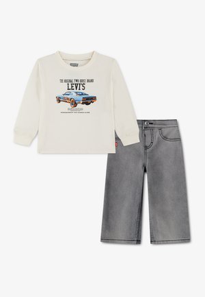 Μπεζ μακρυμάνικο πουκάμισο Levi's με μπλε γραφικό αγωνιστικού αυτοκινήτου, συνδυασμένο με γκρι τζιν σορτσάκι.