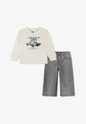 Μπεζ μακρυμάνικο πουκάμισο Levi's με μπλε γραφικό αγωνιστικού αυτοκινήτου, συνδυασμένο με γκρι τζιν σορτσάκι.