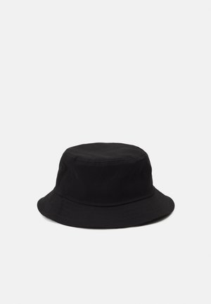 Chapeau seau noir fabriqué en matériau doux et léger, avec une couronne arrondie et un large bord tombant. Design minimaliste, sans logos visibles.