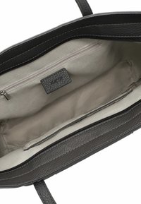 Interior de un bolso de mano de cuero negro con un forro beige, un bolsillo con cremallera y una etiqueta "RUE 09". Presenta un acabado texturizado y dos asas de transporte.