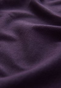 Lilla stof med blød tekstur og subtil glans, der viser blide folder og krøller på overfladen. Ingen tydelige mønstre eller detaljer synlige.