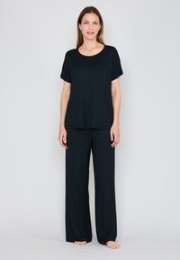 Ensemble de détente noir comprenant un haut ample à manches courtes et un pantalon large, confectionné en tissu doux et léger avec une texture lisse.