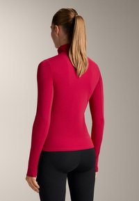 Rød bluse med lange ærmer og høj krave, lavet af elastisk stof, med tætsiddende design og glat tekstur, vist bagfra.