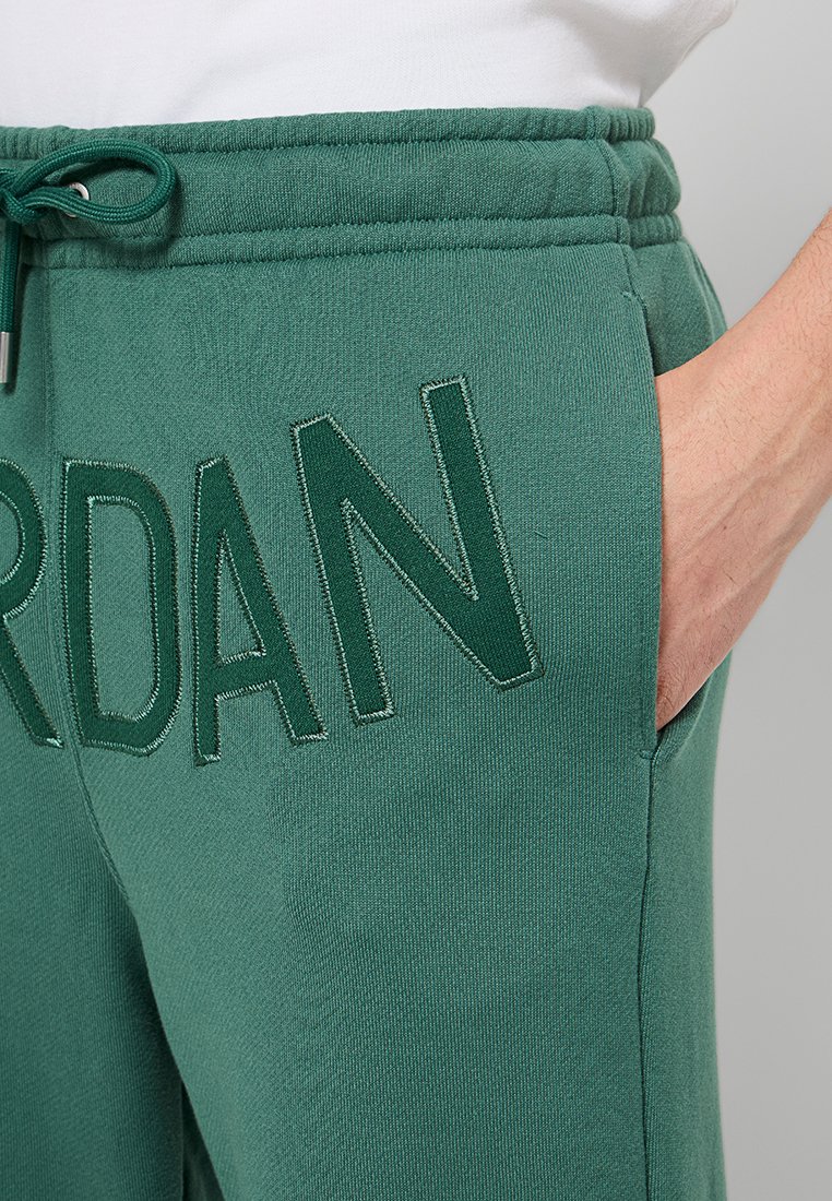 Jogging en coton vert avec une finition texturée, arborant un grand logo brodé "JORDAN" et une taille élastique avec cordon de serrage.