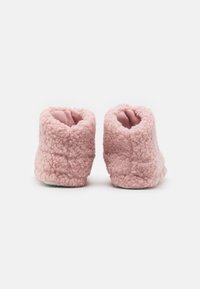 Rosa, fluffiga ankeltofflor med en texturerad yta, öppen topp och mjukt foder. Tjock sula för komfort och värme.