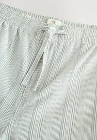 Shorts légers rayés avec un tissu doux et texturé, taille élastique et cordon de serrage, dans des nuances de vert et blanc.