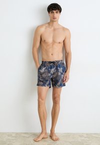 Shorts de baie pentru bărbați în albastru închis, cu un model floral în gri și bej. Sunt dotate cu un brâu elastic și buzunare laterale. Materialul pare ușor.