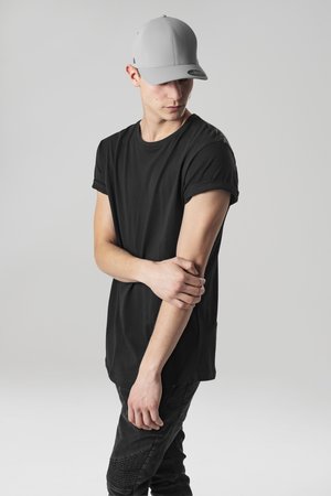 Tricou negru cu maneci scurte, șapcă gri cu boruri curbate, pantaloni negri ajustați cu accente texturate la genunchi. Fundal simplu.