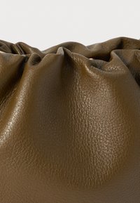 Brown leather bag with a soft, textured surface, featuring a gathered design around the opening, emphasizing a smooth and natural appearance.