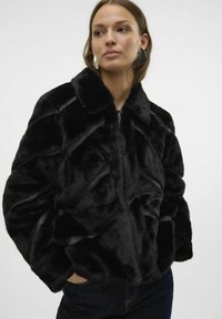 Czarna kurtka z faux futra o diagonalnej teksturze, z kołnierzem i zapięciem na zamek. Posiada boczne kieszenie oraz miękką, gładką powierzchnię.