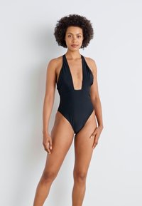 Fato de banho preto em uma peça só, com decote profundo e alças tipo halter, apresentando uma textura suave e um design de perna alta.