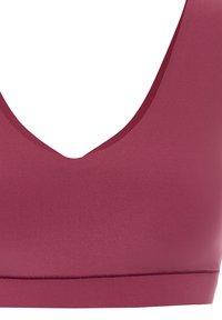 Mauve sports bra with a deep V-neckline and wide straps. Made of smooth, stretchy material with a seamless band. Lightweight and minimal design.