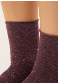 Burgunderrøde sokker med en blød tekstur, der har et subtilt skær fra metalliske tråde, ankelhøjde med ribkant.