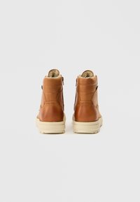 Brune læderankelstøvler med en tekstureret finish, blødt for og cremefarvede såler. Har lynlåslukning på siden.