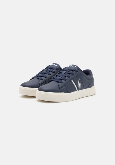 Zapatillas de cuero azul marino con detalles y cordones blancos, que presentan una puntera redonda y suela de goma texturizada. Logo bordado en el costado.