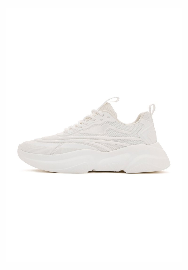 Witte sportieve sneaker met een gestructureerde bovenkant, golfpatronen, dikke gevoerde zool en vetersluiting. Heeft een lus aan de hak.