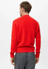 Rdeča pletena jopica z okroglo ovratnikom, rebrastimi manšetami in robom; odlikuje jo gladka tekstura in dizajn raglan rokavov. Prikazan hrbtni pogled.