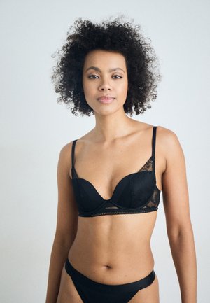Zwart lingeriesetje met een stevige, gevoerde beha met kanten accenten en verstelbare bandjes, gecombineerd met een bijpassende slip.