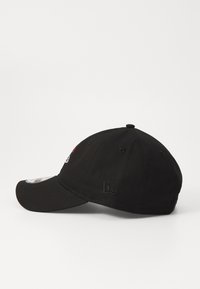 Black baseball cap made of cotton with a curved visor, featuring embroidered logo details, textured fabric, and adjustable strap at the back.