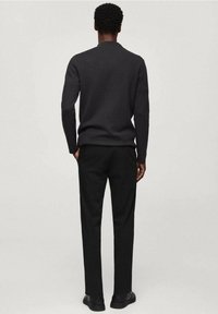 Suéter tejido negro para hombre con cuello redondo, combinado con pantalones negros a medida y zapatos negros, mostrado de espaldas.