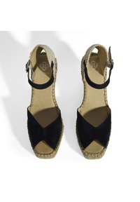 Sandales espadrilles en daim noir avec un design croisé, talon en jute, bride de cheville et accents en fibres naturelles texturées.