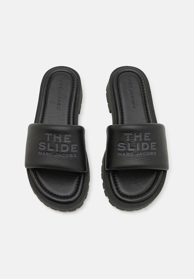 Sorte sandaler med teksturert lærstropp som har ordene "THE SLIDE" og "MARC JACOBS" preget. Gummiyttersåle med grep.