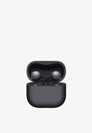 Black wireless earbuds resting in an open charging case with a small green indicator light on the front.