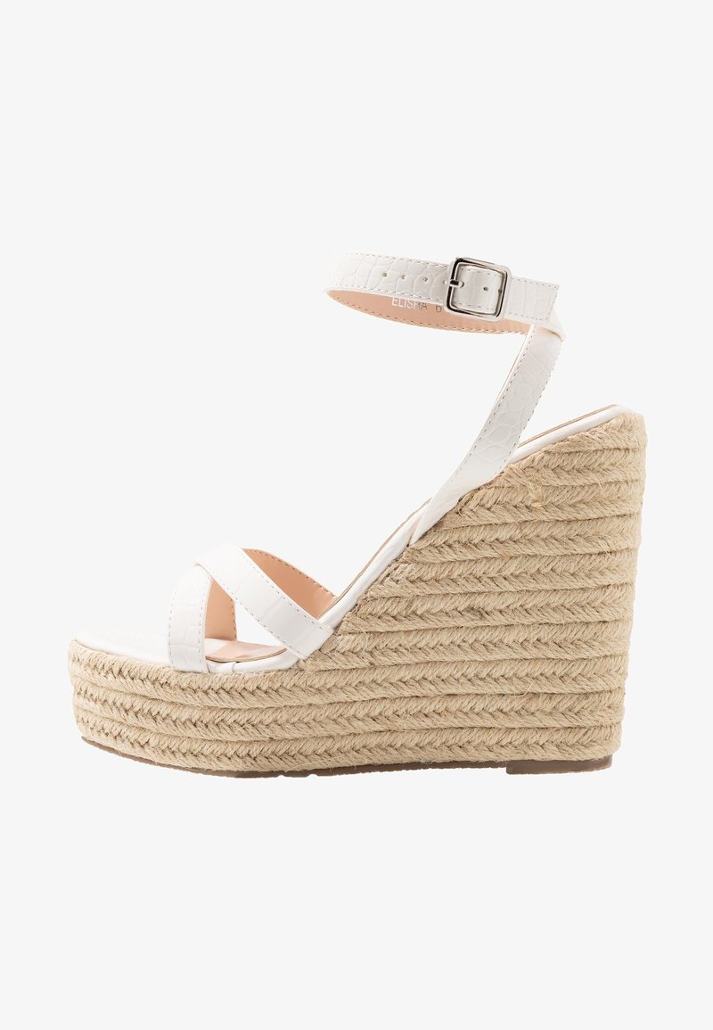 Sandale compensée blanche à plateforme avec une bride texturée et brillante ainsi qu'une boucle de cheville ajustable. Talon compensé enveloppé de jute pour plus de hauteur et de stabilité.