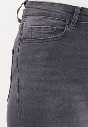 Close-up af mørkegrå cowboybukser med synlig bæltestrop, forlomme og møntlomme med synlige syninger.