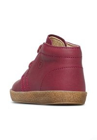 Scarpa in pelle magenta con suola testurizzata e punta tonda. Presenta un design alto con dettagli cuciti e un logo laterale.