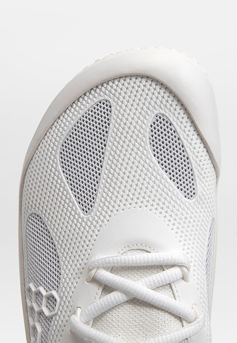 Weißer Sportschuh mit einem Obermaterial aus Mesh, das strukturierte Muster und hexagonale Akzente aufweist, abgerundete Zehen und flache Schnürsenkel.