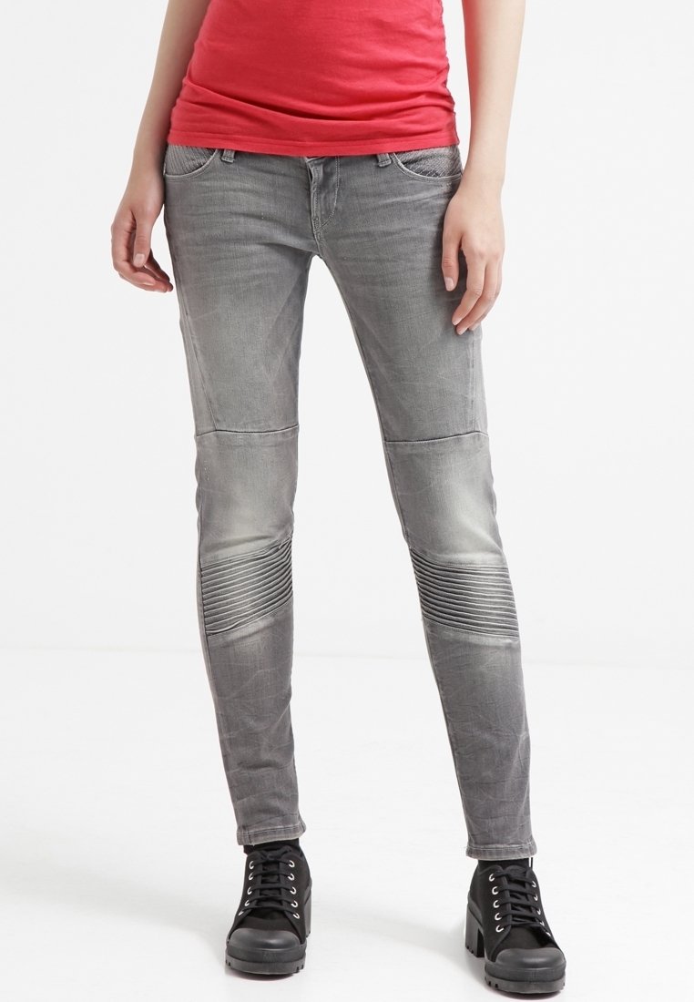 Jeans gris de corte slim con detalles acanalados en las rodillas, que cuentan con cinco bolsillos y un acabado desgastado. Combinados con botas de tobillo negras con cordones.