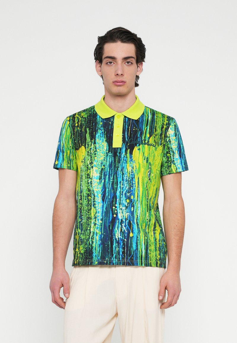 Polo med en lys blå og grøn abstrakt malermønster, med en gul krave og en åbning med tre knapper. Korte ærmer.