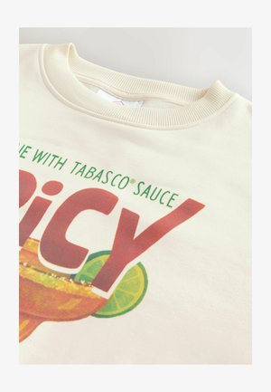 T-shirt col rond de couleur crème avec texte partiel « with Tabasco® Sauce » et grand « Spicy » rouge sur un dessin de verre margarita et tranche de citron vert.