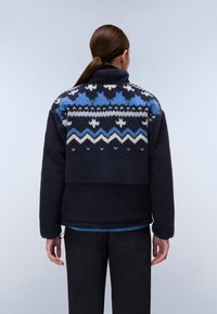 Giacca in fleece navy con un motivo geometrico blu e bianco. Collo alto, design corto e tessuto texturizzato. Maniche lunghe.