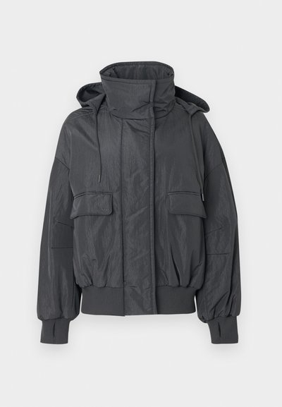 Tamsiai pilka trumpa pūkinė striukė su aukštu apykakliu, nuimamomis gaubtu, dviem priekinėmis kišenėmis, ribbinguotais rankogaliais ir lygiu, tekstūruotu paviršiumi.