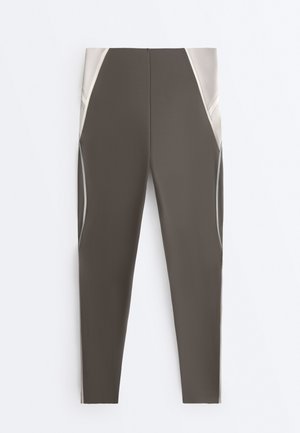 Olive green and beige high-waist leggings with panel detailing and seam lines, designed for activewear.