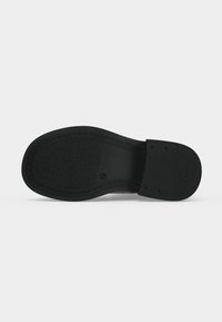 Semelle de chaussure noire avec grip texturé et talon lisse, affichant la taille 37, photographiée sur un fond clair uni.