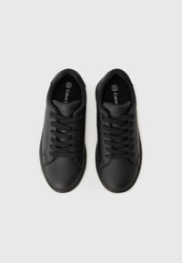 Svarta lädersneakers med rund tå, platta snören, texturerade paneler och logotyp på tungan. Slät yta med subtila perforeringar.